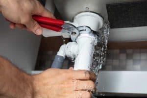 a person fixing a leaky faucet or pipe