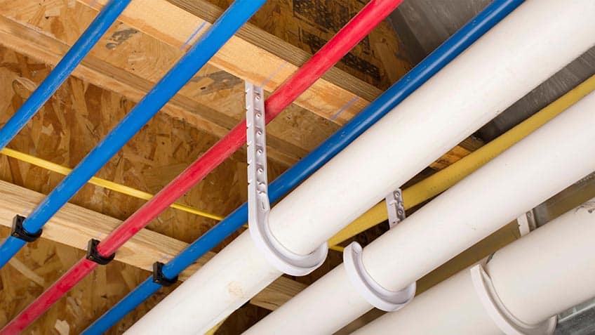 Pex and Drain Pipes Attached to the Basement Ceiling of a Home